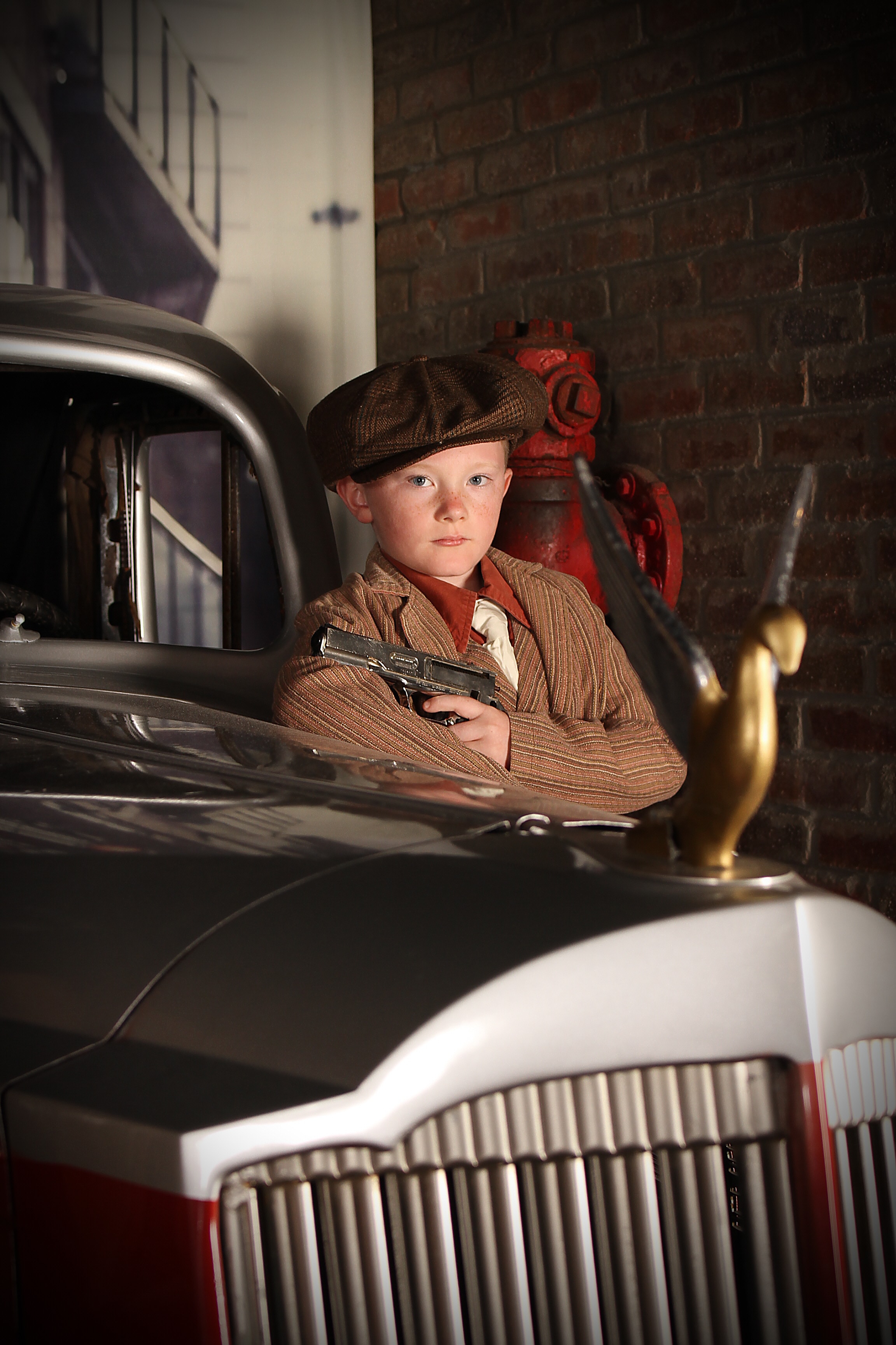 Child in 1920s gangster costume by vintage car