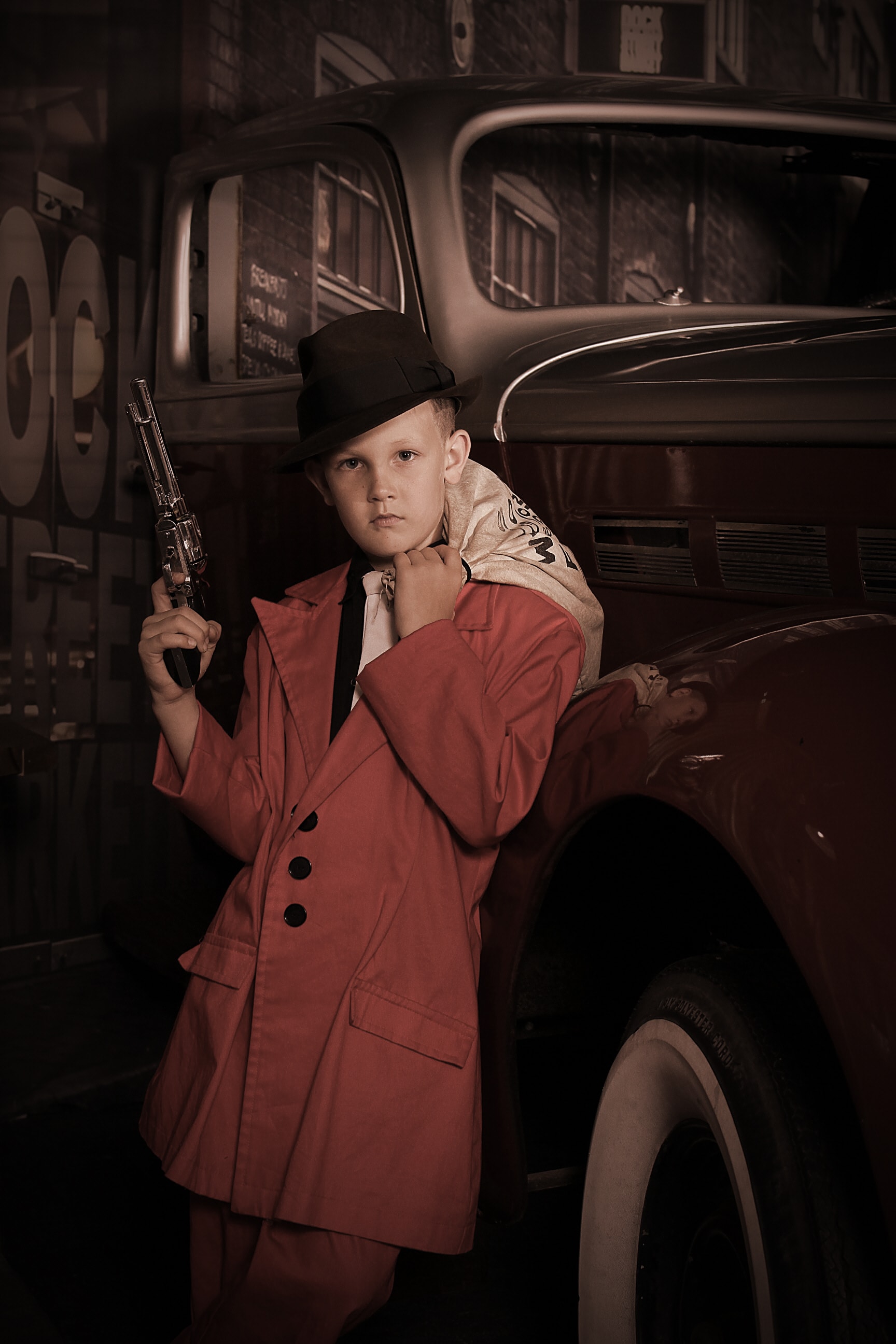 Boy in red gangster suit leaning on vintage car