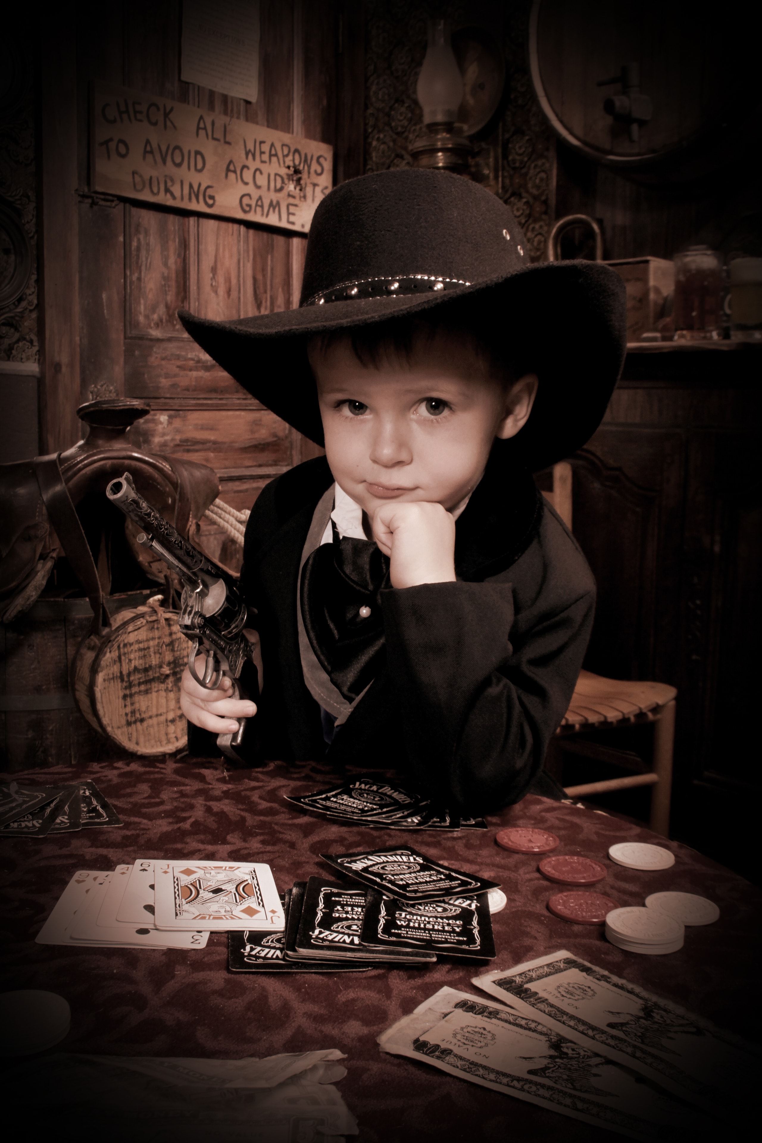 Boy in cowboy hat at poker table with cards and chips