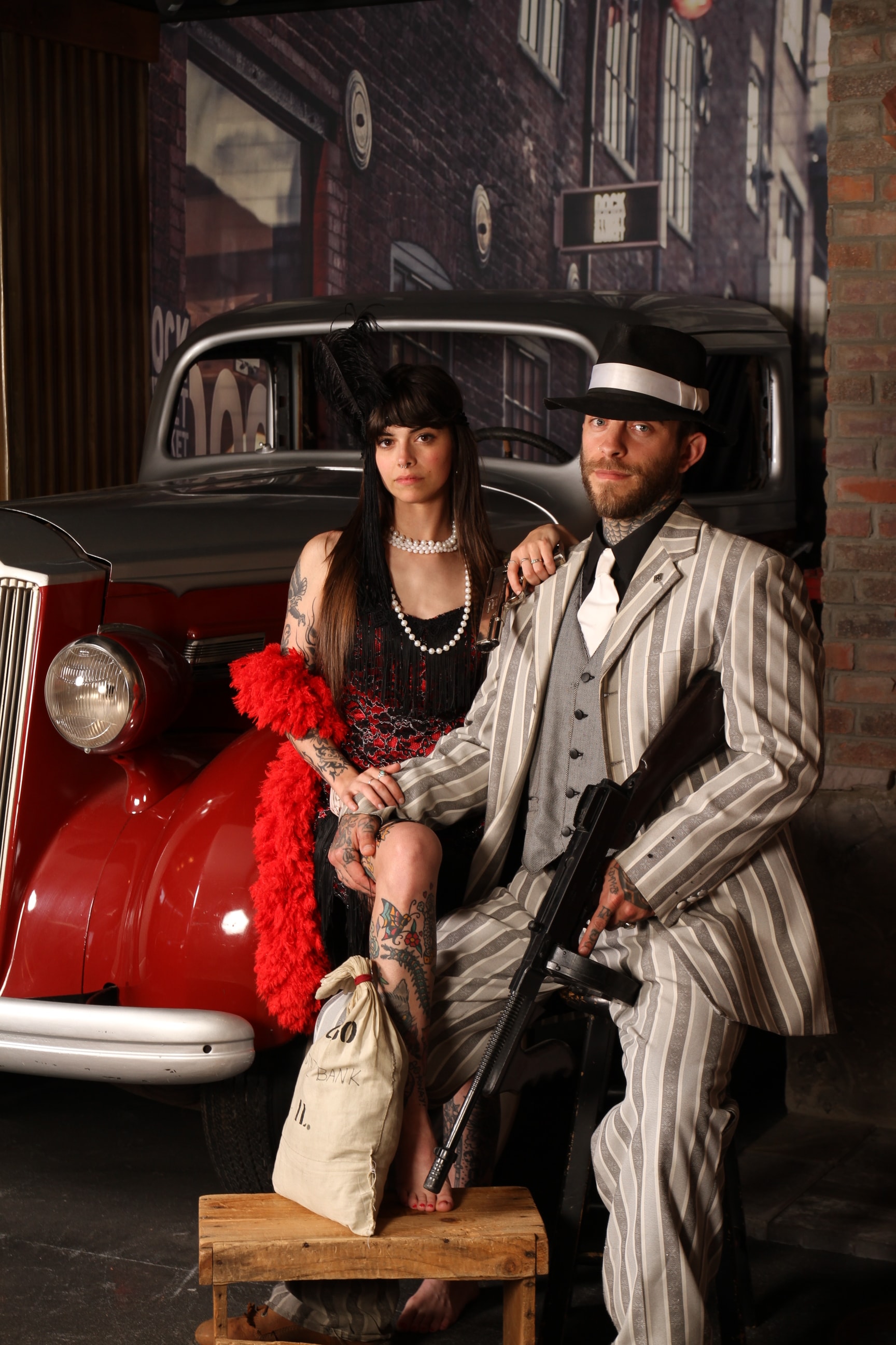 Couple in 1920s gangster costumes by vintage car